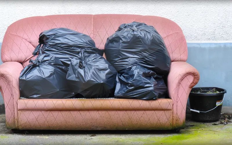 An old sofa and bags of rubbish awaiting collection